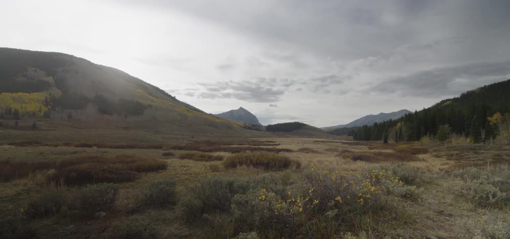 Dark clouds are drifting over a valley during the day