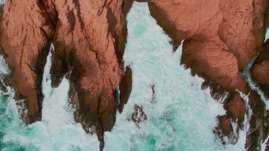The blue waters splash against the rocks below