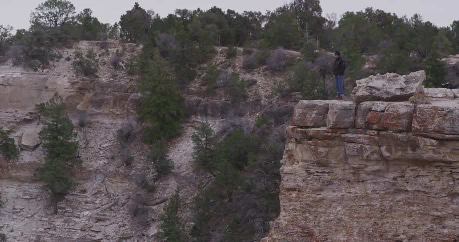 Man taking pictures at the edge of a cliff