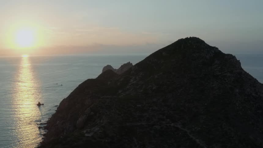 Waves are rolling over rocks and splashing against cliffs at sunset