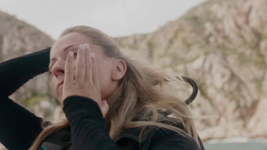 A diver pulls back her hair while riding in a boat