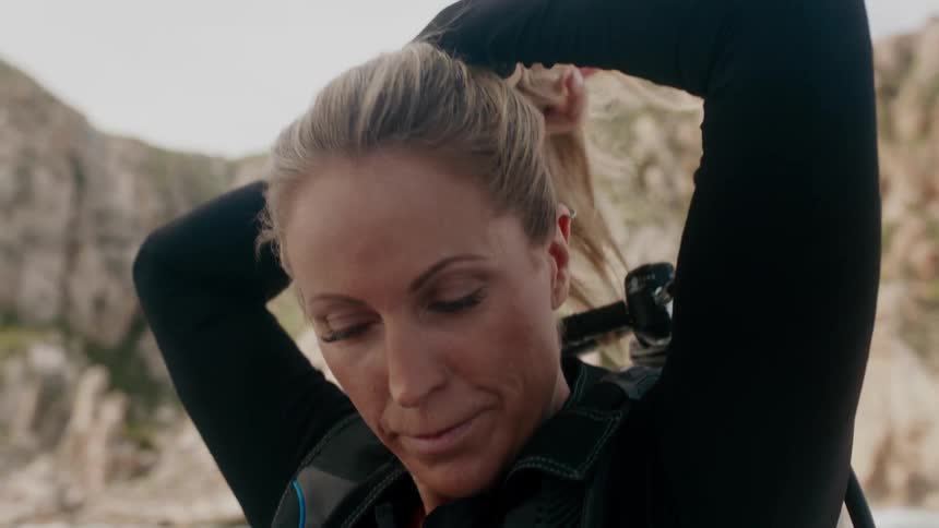 A woman outside putting her hair into a ponytail