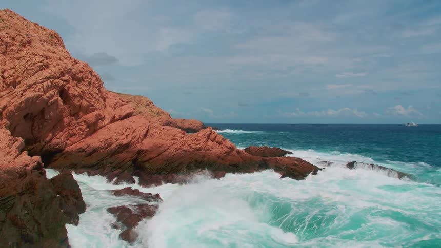 Waves crashing against a rocky orange shore