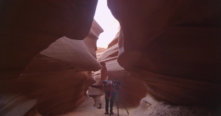 A hiker takes a photograph in a canyon