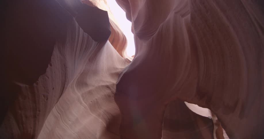 The camera pans inside a rocky sandstone crevice towards the sky above