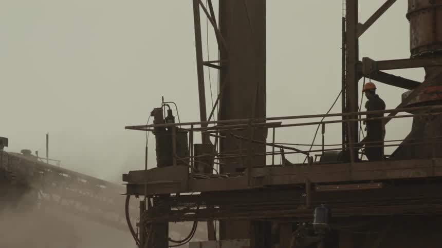 iron dust floats around a worker on a platform