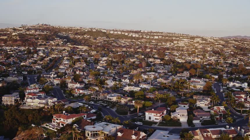 Houses and streets sprawl across a mesa in a coastal community on a smoggy day