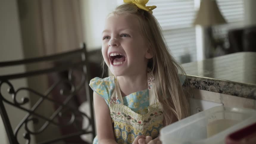 Young girl laughing when a woman touches her nose indoors