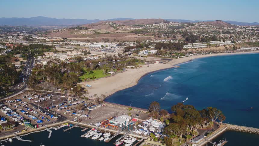 Waves are rolling towards a beach in a coastal community on a sunny day