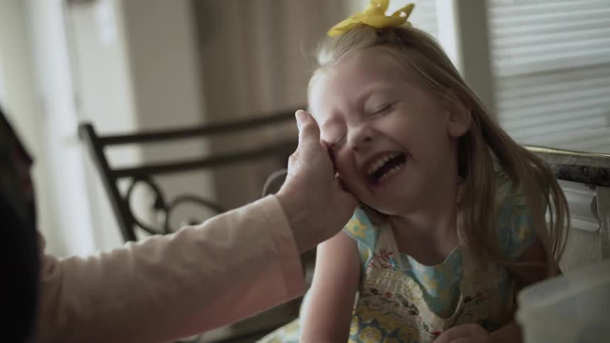 A woman touches the face of a laughing girl
