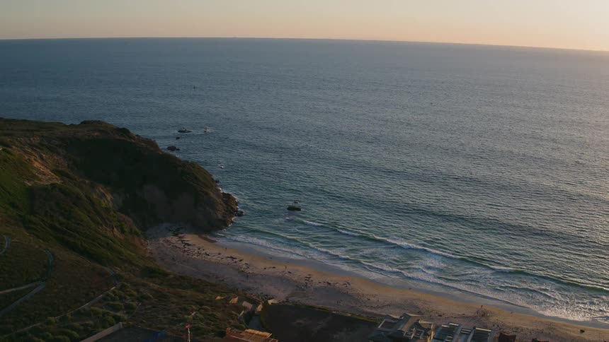 The sun is setting over the blue waters of the shore