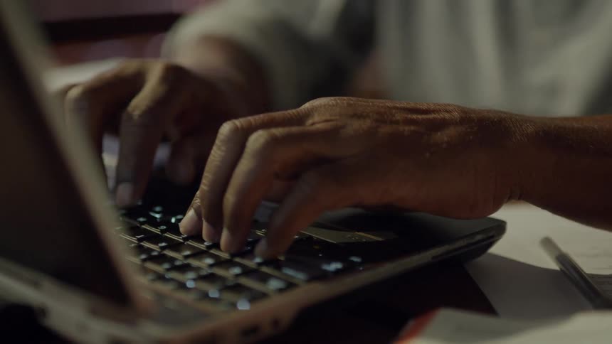 A man flips the page of a book and begins typing