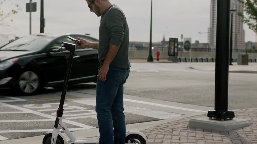 A person gets on an electric scooter and drives away