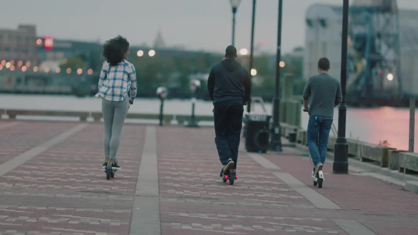 People riding scooters over brick walkways