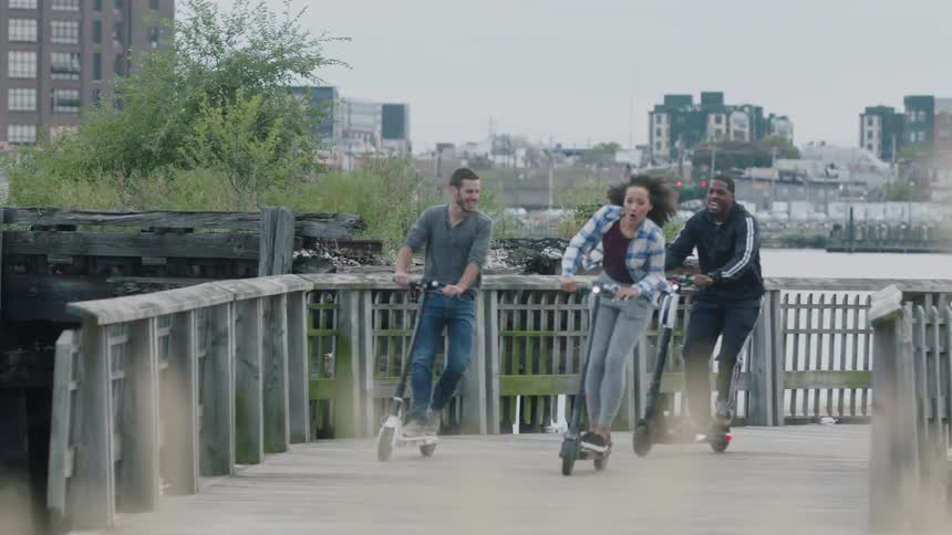 People ride scooters over a pier