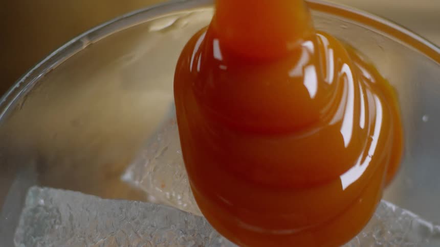 Thick orange liquid poured over ice
