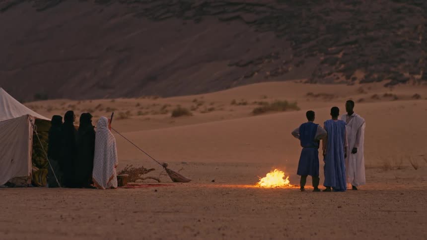 People stand around a campfire in the desert
