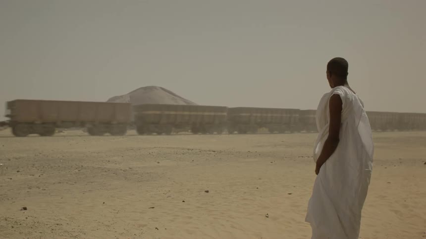 A man in white watches a train pass by