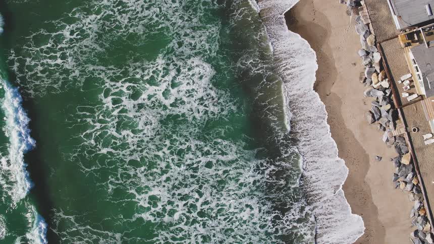 Waves crash against the sunny shore below