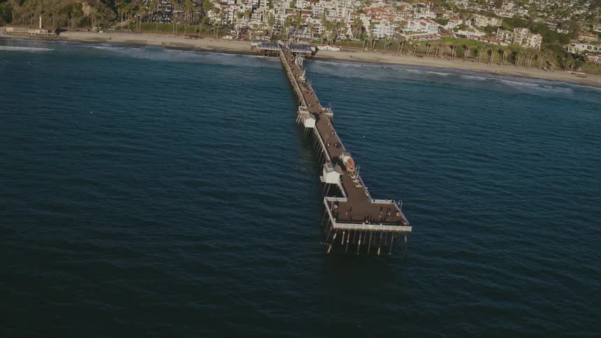 Pier reaching out into the sea from the shore of a civilized area