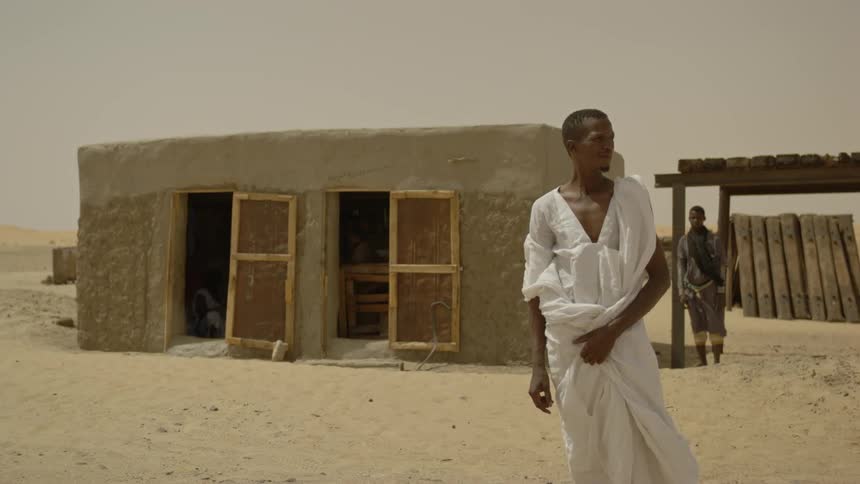 Men stand outside a hut in africa in the desert during the day