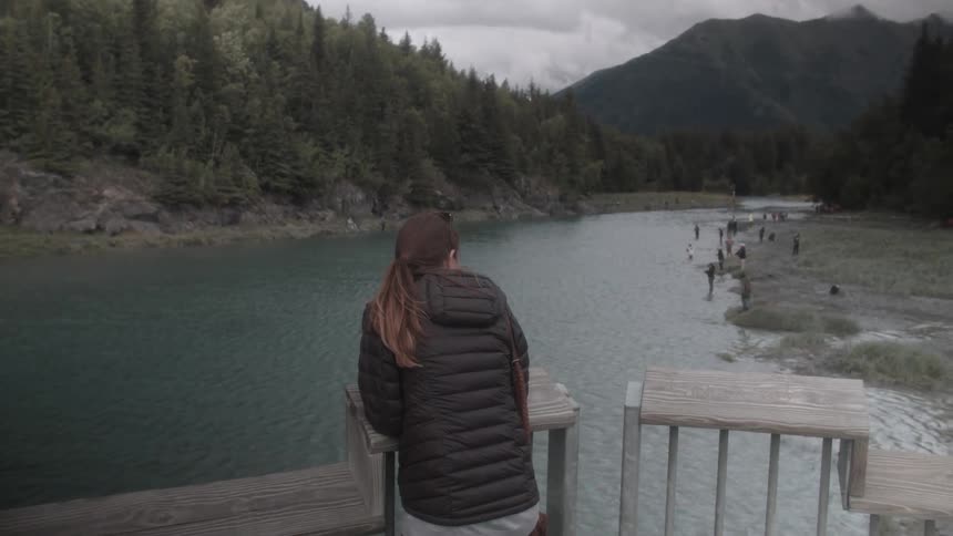 A woman looks at a mountain lake