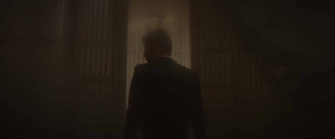 A man in a suit walks through a hazy room