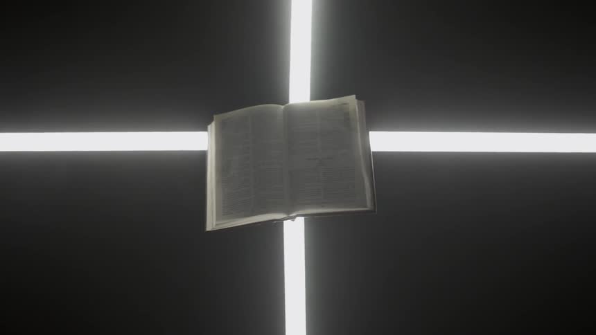 An open book sits on glowing strips of light