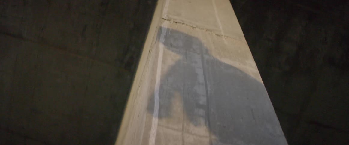 A shadow of a person is cast on a cement column