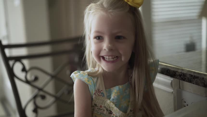 A young girl has flour sprinkled on her nose in the kitchen