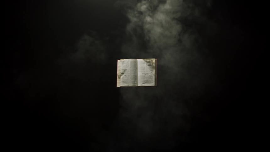 Smoke pours into a dark room with a suspended book