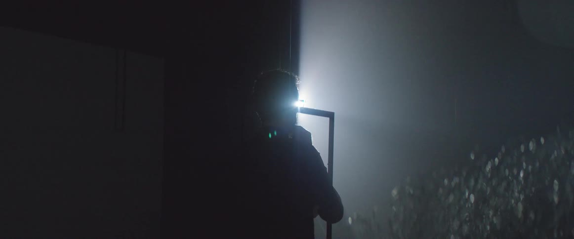 Light shines on a man in a dark room