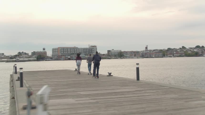 The three people ride their scooters around on the pier