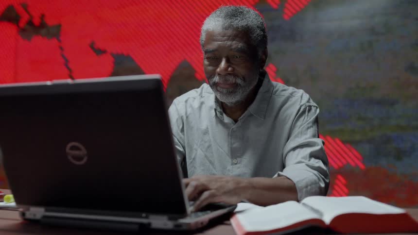 A man works on computer in front of LED wall