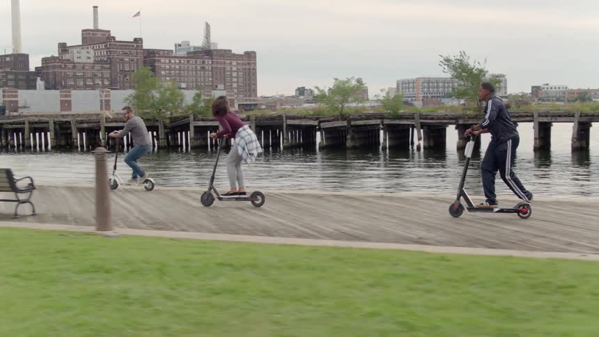 People riding scooters near water