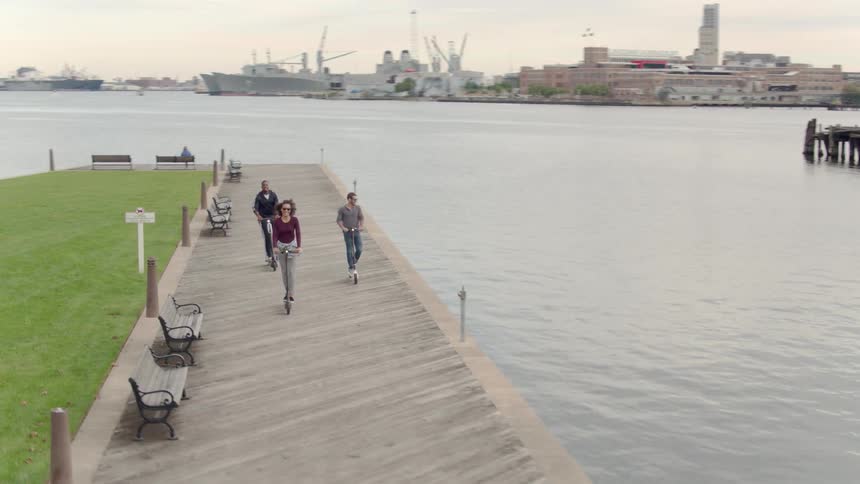 Three people ride their scooters on a cloudy day