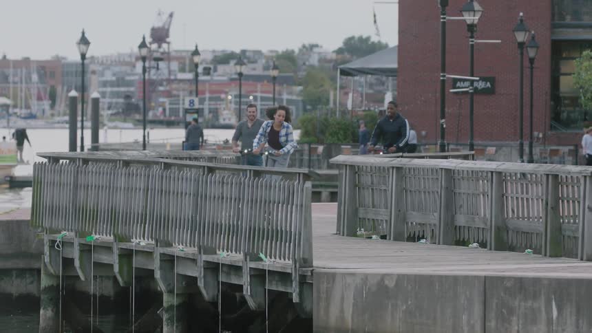 Friends ride scooters on a pier