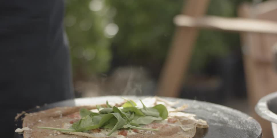 Spinach leaves drop onto a piece of meat smoking on a flat top