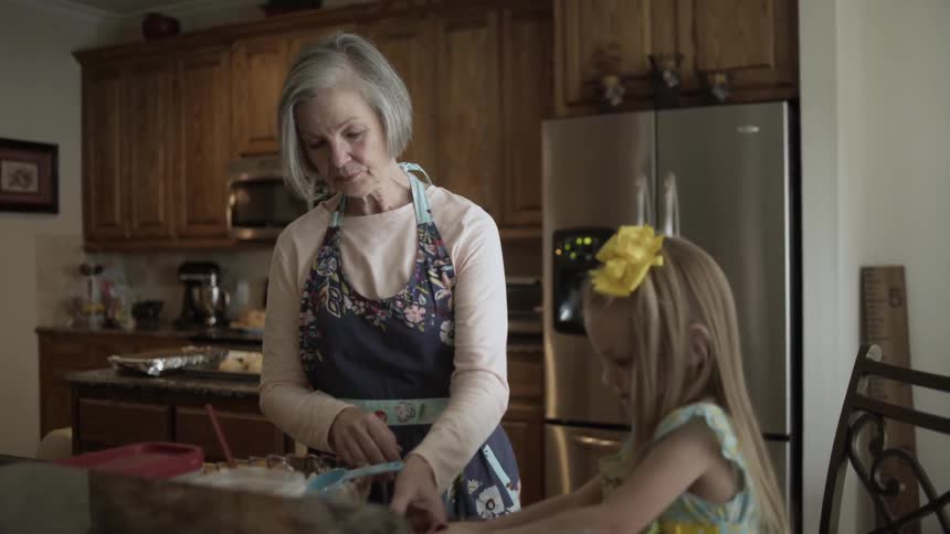 An older woman and young girl are making something in the kitchen
