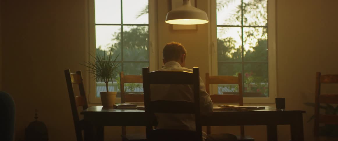 A man sits at the dining table and reads