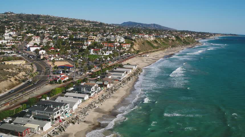 The waves crash against the shore of the coastal town