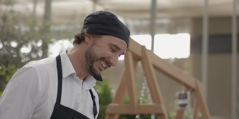 A man is smiling as he works inside during the day