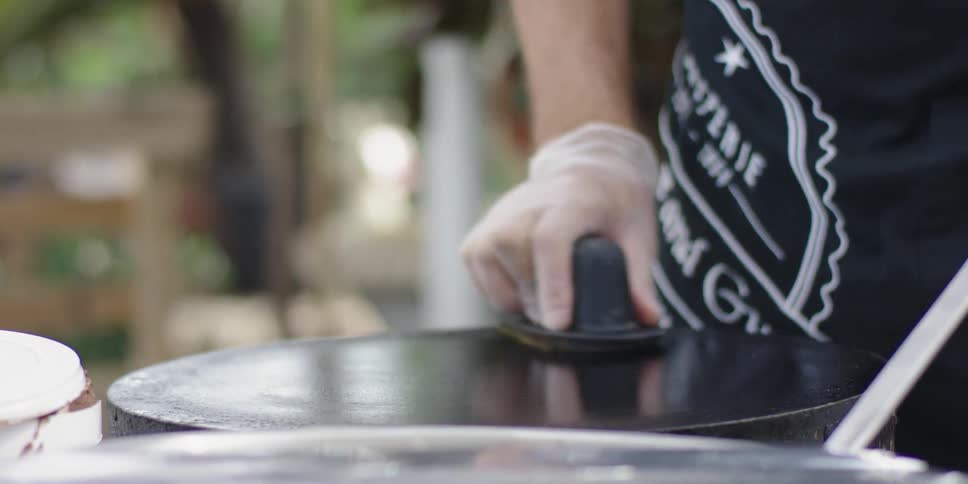 A man wipes the top of an outdoor stove top