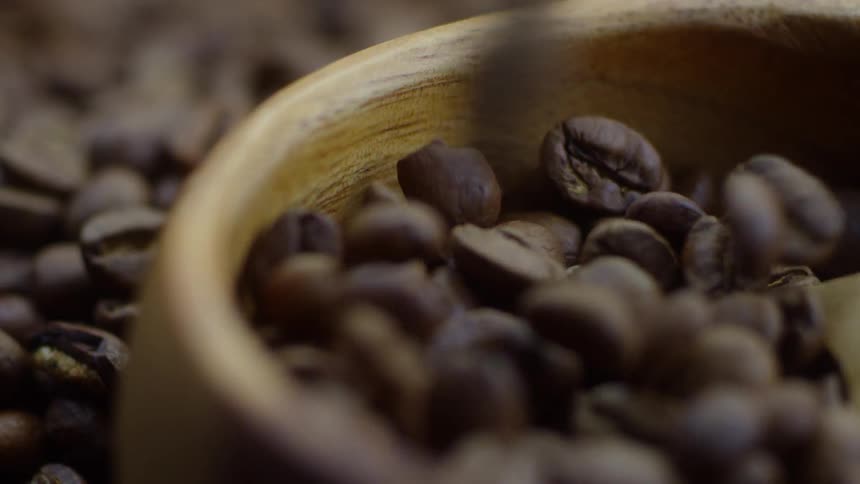 Coffee beans are pouring into a container and spilling out