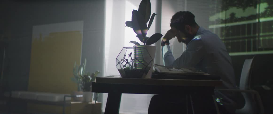 A man sits at a desk as images are projected on the wall