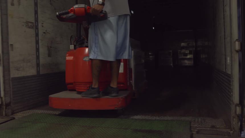 A forklift operator is driving a pallet of goods into a truck during the day