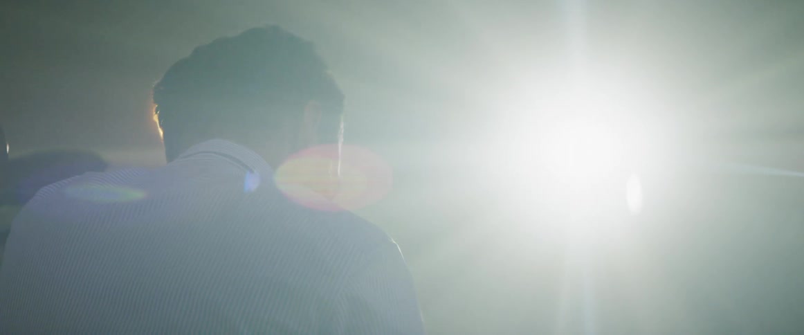 Light shines on a man in a blue striped shirt