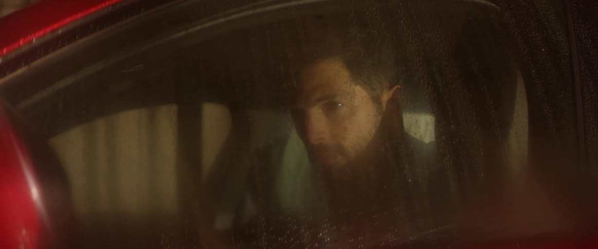 A man sits in a car looking out the side window