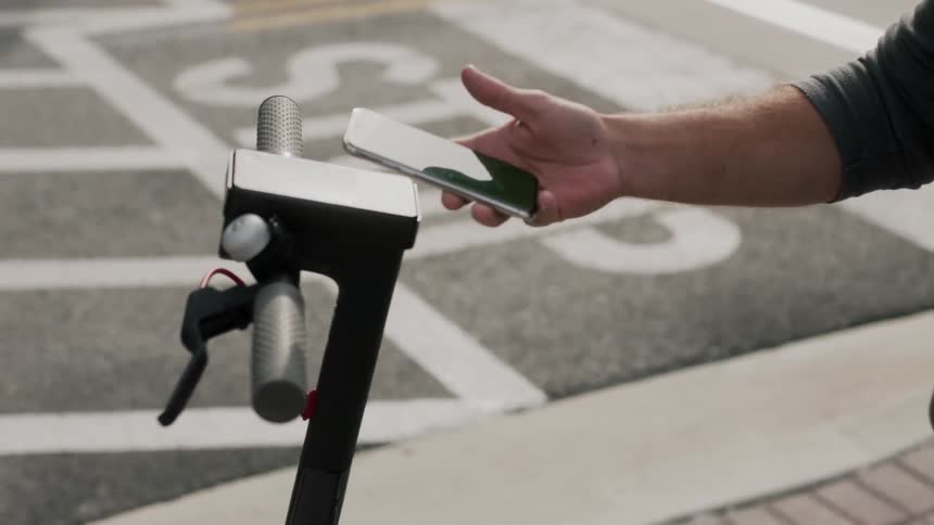 A person checks out a scooter using his phone