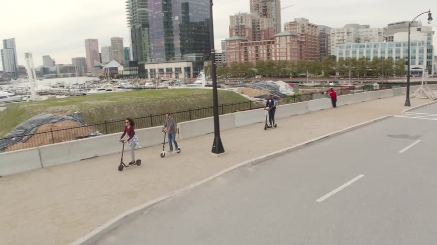 Friends are riding scooters through a city during the day
